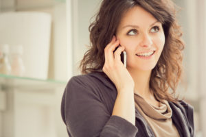 young smiling brunette woman with phone in the kitchen